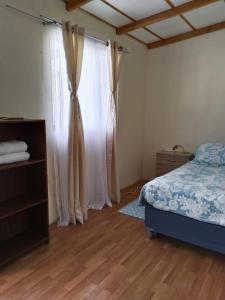 a bedroom with a bed and a window with curtains at Casa Dorada in San Pedro de Atacama