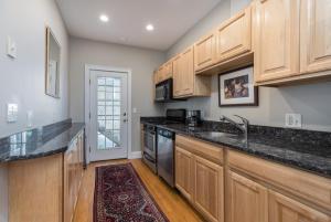 uma cozinha com armários de madeira e bancadas pretas em Sunny convenient home w/ private patio! Easy walk to everything! em Boston