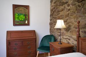 1 dormitorio con cómoda, silla y lámpara en Casa das Infusões - Soalheiro, en Melgaço