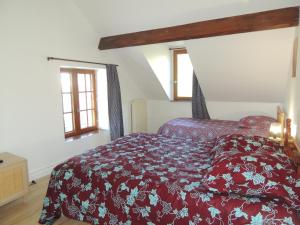 a bedroom with a bed with a red comforter at LA VILLA QUI A DU CHIEN in Neuville-sur-Touques
