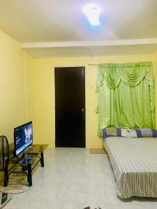 a bedroom with a bed and a television and a door at Perlies Inn Studio House with NETFLIX in Tanay