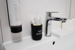 a bathroom sink with a toothbrush holder next to a faucet at Gästehaus Estenfeld bei Würzburg 24 h in Estenfeld