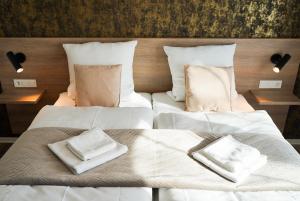 Dos camas en una habitación con sábanas y almohadas blancas. en Gästehaus Würzburg 24h, en Estenfeld