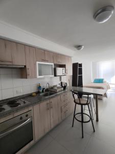 a kitchen with wooden cabinets and a table and a bed at Sector Av. Brasil 1D1B - 4P edificio in Antofagasta