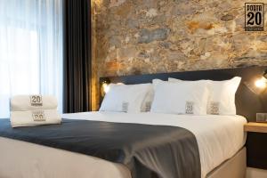 a bedroom with a large bed with a stone wall at Porta 20 Boutique Guesthouse in Leiria