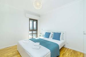 a white bedroom with a large bed with blue pillows at Matosinhos Wonderfull apartment by Innkeeper in Matosinhos