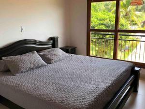 a bedroom with a bed with a large window at Finca la Bonita, Barbosa, Antioquia. in Barbosa