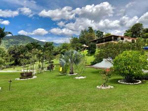 a garden with trees and a house in the background at Finca la Bonita, Barbosa, Antioquia. in Barbosa