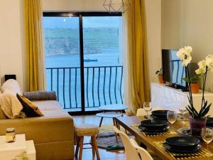 ein Wohnzimmer mit einem Tisch und einem großen Fenster in der Unterkunft Porto Vita SeaView Apartment in St Paul's Bay