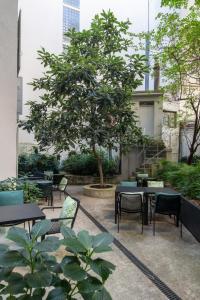 d'une terrasse avec des tables, des chaises et un arbre. dans l'établissement Hôtel Pax, à Genève
