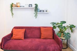 - un canapé rouge avec deux oreillers orange dans le salon dans l'établissement Appartement 1 ch à 1 min de la plage des Catalans, à Marseille