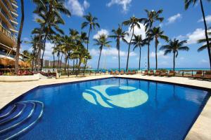 einen Pool mit Palmen und dem Meer in der Unterkunft OUTRIGGER Waikiki Beach Resort in Honolulu