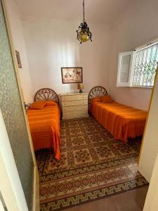 スコペッロにあるVilla Cactusのベッドルーム(オレンジのシーツ、ラグ付)のベッド2台