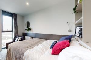 a bedroom with a large bed with red and blue pillows at Studio Apartments and Ensuite Bedrooms with Shared Kitchen at Chapter Ealing right next to North Acton Tube Station in London