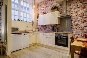 a kitchen with white cabinets and a brick wall at Flat 2, The Old Antiques Warehouse - FREE off-site Health Club access with Pool, Sauna, Steam Room & Gym in Bowness-on-Windermere