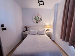 1 dormitorio blanco con 1 cama grande con sábanas y almohadas blancas en Hospedería El Caravansar, en Frigiliana