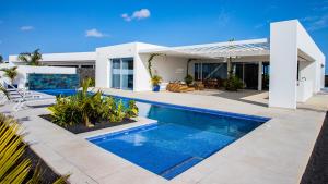 uma villa com piscina em frente a uma casa em Golf Palms em Costa Teguise