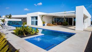 a villa with a swimming pool in front of a house at Golf Palms in Costa Teguise