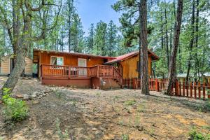 a cabin in the woods with a fence and trees at Cozy Lakeside Escape with Deck 4 Mi to Rainbow Lake in Pinetop-Lakeside