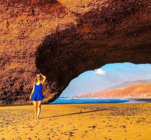a woman walking through a cave on the beach at Appartement, tilila in Mirleft