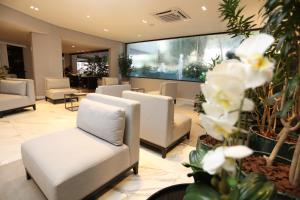 a waiting room with white chairs and flowers at Hotel Trianon Paulista in São Paulo