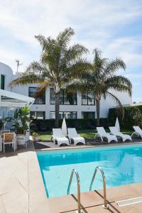 una piscina con tumbonas blancas y palmeras en Hotel L'Algadir del Delta, en El Poblenou del Delta