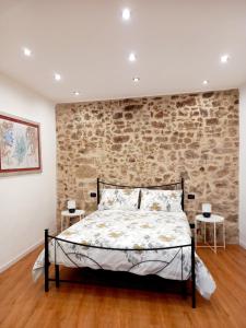 um quarto com uma parede de tijolos e uma cama em Antica Sicilia Luxury em Regalbuto