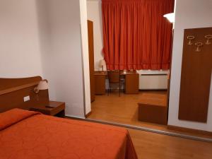 CastelgombertoにあるAlloggio Al Ponteのベッドルーム1室(ベッド1台、デスク、赤いカーテン付)