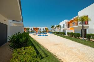 a pathway leading to a resort with a swimming pool at Jardins de Pêra in Pêra