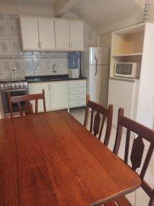 eine Küche mit einem Holztisch mit Stühlen und einem Kühlschrank in der Unterkunft Residencial Andorinhas in Bombinhas
