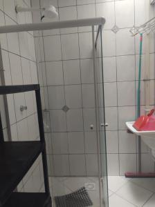 a shower with a glass door next to a sink at Residencial Andorinhas in Bombinhas