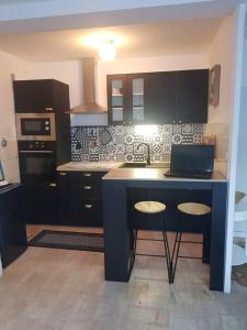 uma cozinha com armários pretos e um balcão com bancos em Magnifique T2 au centre ville em Cluses