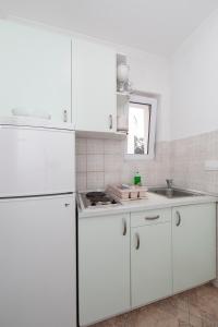 a white kitchen with white cabinets and a sink at Villa Fina in Tučepi +88 photos