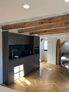 a kitchen with black cabinets and a wooden ceiling at O verso du Château - STUDIO 22 in Barr
