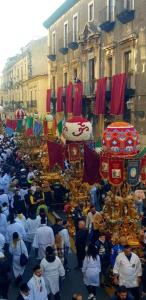 uma multidão de pessoas andando por uma rua com um desfile em B&B Kike em Catânia