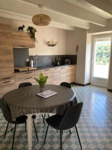 ein Esszimmer mit einem Tisch und Stühlen sowie eine Küche in der Unterkunft Gîte Miss Cardabelle in La Bastide-Pradines