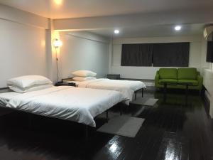 um quarto de hospital com duas camas e uma cadeira verde em Baanmali Ari em Pathum Thani