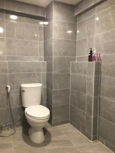 a bathroom with a toilet and a tiled wall at Baanmali Ari in Pathum Thani