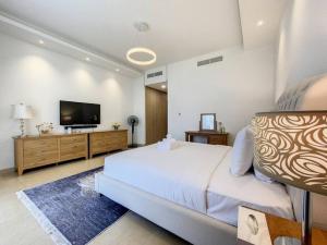 a bedroom with a large bed and a flat screen tv at Key View - Villa Gardenia Jebel Ali in Dubai