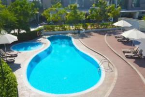 une piscine dans un hôtel avec des chaises et des parasols dans l'établissement Key View - Villa Gardenia Jebel Ali, à Dubaï