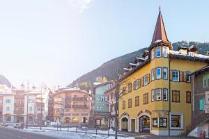 ein gelbes Gebäude mit einem Turm auf einer Straße in der Unterkunft Ciasa Gianot - Shin in Moena