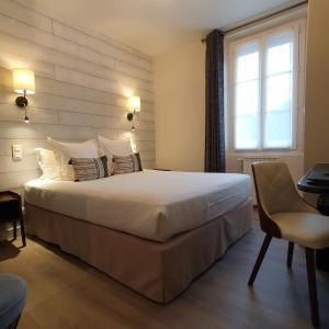 a bedroom with a large white bed and a window at Logis Hotel La Closerie in La Baule