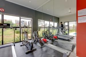 a gym with cardio equipment in a building with windows at Cosy Butterfly Comforts 2 Bed Top Floor Unit in Fourways
