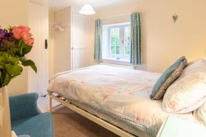 a bedroom with a bed and a window and a chair at Sunny Beck Cottage - Norfolk Cottage Agency in Mundesley