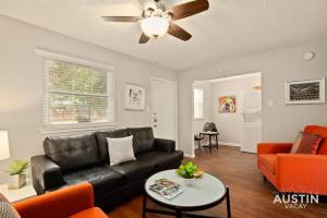 a living room with a black leather couch and orange chairs at Austin East Side on Manor Rd in Austin