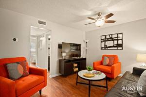 a living room with orange chairs and a ceiling fan at Austin East Side on Manor Rd in Austin