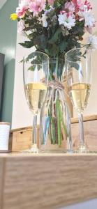 dois copos de vinho branco e um vaso de flores em La Maison des Délices em Dosches