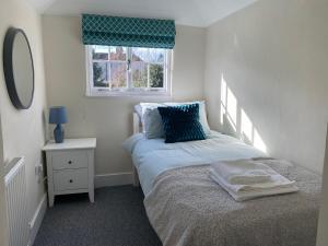 ein kleines Schlafzimmer mit einem Bett und einem Fenster in der Unterkunft Cheerful 2 Bedroom Cottage in Central Canterbury in Kent