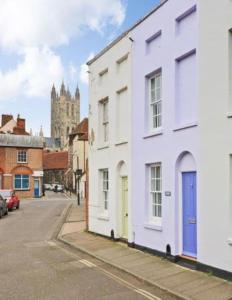 ein weißes Gebäude mit blauer Tür auf einer Straße in der Unterkunft Cheerful 2 Bedroom Cottage in Central Canterbury in Kent