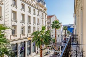 a city street with palm trees and buildings at Snow YourHostHelper in Cannes